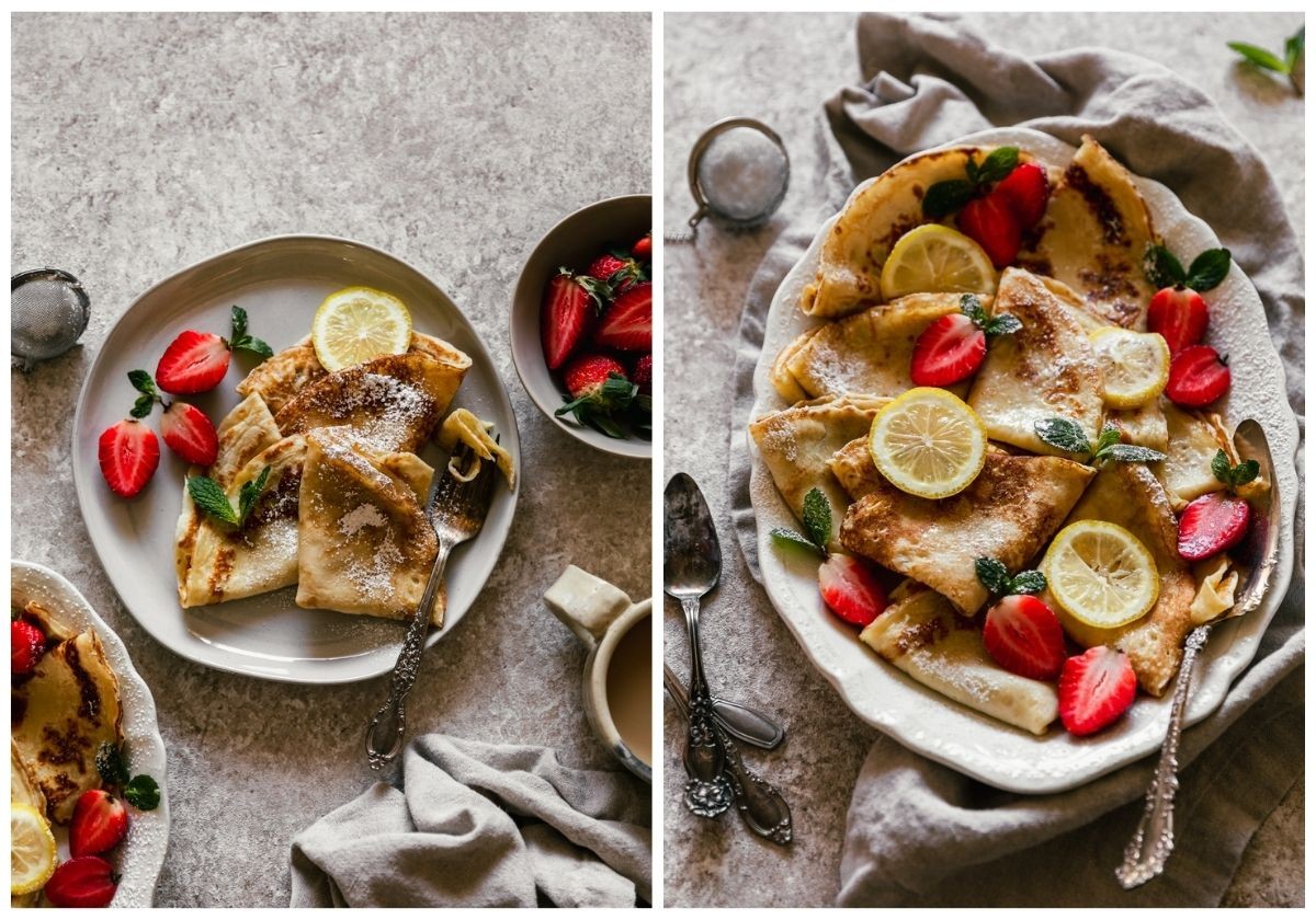 Two images; on the left, a white plate with Norwegian pancakes, berries, and a lemon slice on a tan counter next to a bowl of berries, a tray of pancakes, and a beige linen. On the right, a closeup side image of a white oval tray of pancakes with berries and lemons on a beige linen next to vintage spoons.
